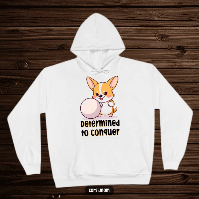 Funny, cozy hoodie featuring a determined Corgi pushing a large bouncy ball, perfect for staying warm and motivated.
